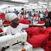 Dignity factory workers in Accra, Ghana, producing shirts for overseas clients. The company aims to enhance worker-factory relationships by providing free, good-quality meals, an in-house clinic, and efforts to create a social life for workers.