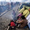 A mother holds her crying child, as her three other daughters sit by the fire outside their makeshift tent in Idomeni, Greece.