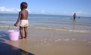 A small boy holds onto a bucket as he wades on the beach in Anosikely, a neighbourhood in Morondava, Madagascar. Behind him, women use nets to fish.