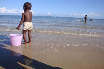A small boy holds onto a bucket as he wades on the beach in Anosikely, a neighbourhood in Morondava, Madagascar. Behind him, women use nets to fish.