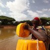Una mujer somalí saca agua de un estanque hecho con apoyo del PNUD para aliviar a las comunidades afectadas por la sequía. Foto: PNUD Somalia