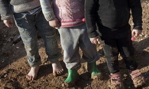 Syrian children, including one who is barefoot, stand atop the muddy ground in the Bab Al Salame camp for internally displaced persons, near the border with Turkey, in Aleppo Governorate.