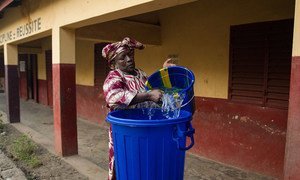 Une enseignante en Guinée prépare un seau d'eau pour se laver les mains. Photo MINUAUCE/Martine Perret