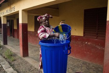 Une enseignante en Guinée prépare un seau d'eau pour se laver les mains. Photo MINUAUCE/Martine Perret