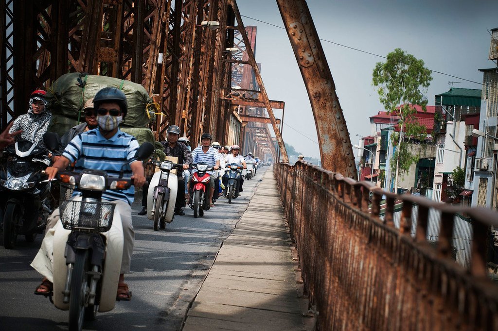 Motocicletas atravessam a Ponte Long Bien sobre o Rio Vermelho em Hanói, Vietnã.
