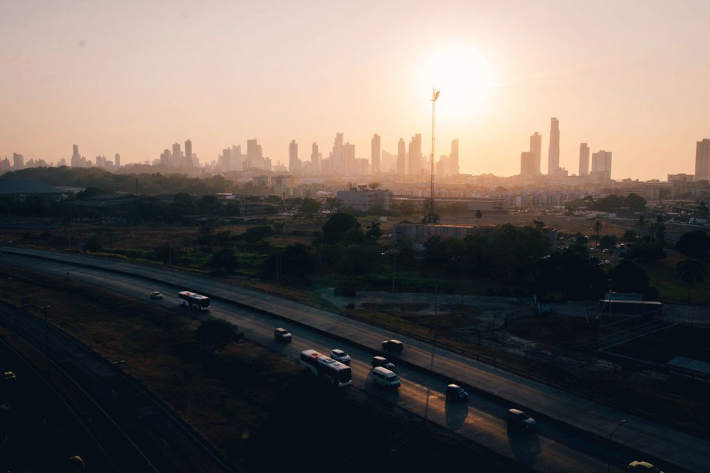Vista del horizonte de la Ciudad de Panamá al amanecer, con el tráfico circulando por una autopista en primer plano.