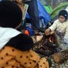 Two little boys warm up by a fire outside the camping tent that has been provided for them by humanitarian organisations in Idomeni, Greece.