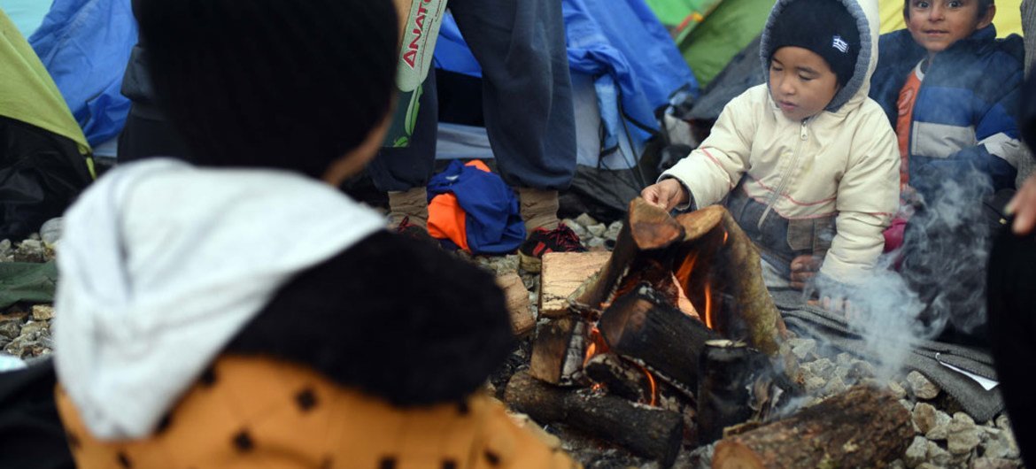Two little boys warm up by a fire outside the camping tent that has been provided for them by humanitarian organisations in Idomeni, Greece.