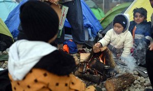 Two little boys warm up by a fire outside the camping tent that has been provided for them by humanitarian organisations in Idomeni, Greece.