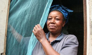A woman putting up a mosquito bednet in Tanzania.