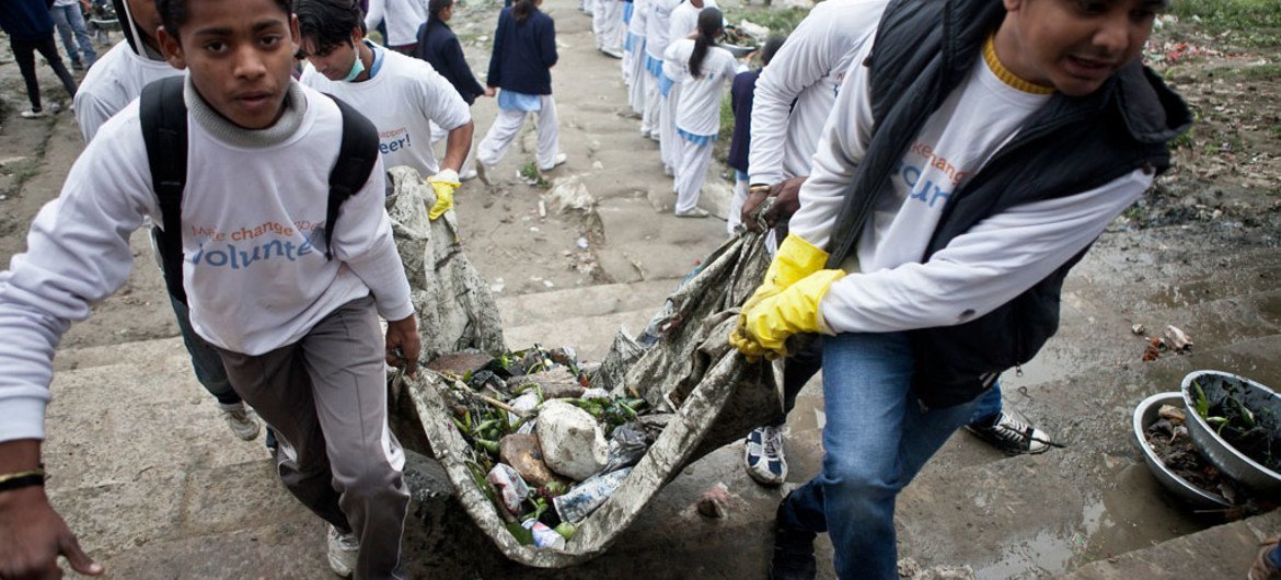 Young volunteers clean garbage from the Yamuna River banks in India.