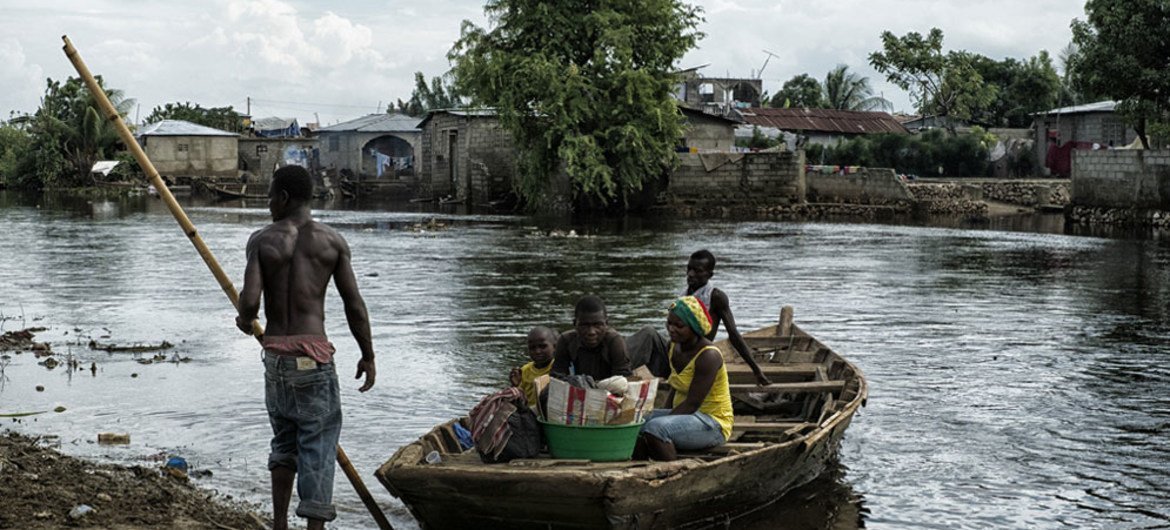 أسرة في كاب هايتين هايتي، متن قارب أثناء الفيضانات في عام 2014. المصدر الأمم المتحدة / لوغان عباسي