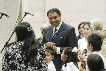 Feu l’ancien boxeur Muhammad Ali (au centre), Messager de la paix des Nations Unies et triple champion du monde des poids lourds, lors d'une cérémonie pour la Journée internationale de la paix en 2004, au siège de l'ONU, à New York. Photo : ONU / Ky Chung
