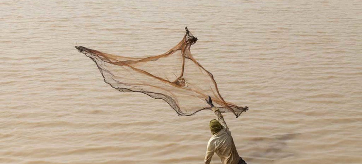 un pêcheur jetant son filet dans le bassin d'Arikouka, à Tera, au Niger.