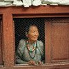 Пожилая женщина смотрит из своего окна в одной из деревень  в Непале. Фото ООН