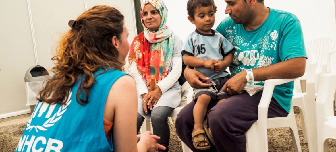 غلام علي جعفري، وزوجته نبيلة، وابنهما البالغ من العمر عامين أمير، يتحدثون مع موظفي المفوضية في انتظار استلام وثائقهم من دائرة اللجوء اليونانية. المصدر: مفوضية الأمم المتحدة للاجئين / أخيلياس زفاليس