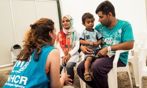 Ghulam Ali Jaffari, sa famme Nabila, et leur fils de 2 ans Amir parlent avec une employée du HCR en attendant de récupérer leur document d'identité du Service grec d'asile. Photo HCR/Achilleas Zavallis