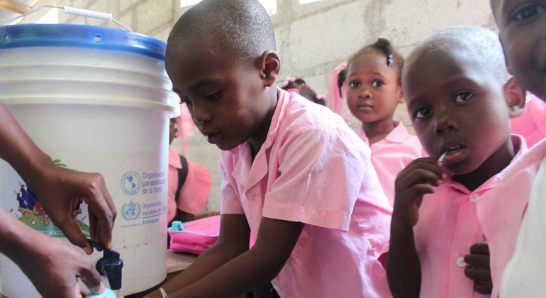 Un grupo de niños haitianos aprende cómo lavarse las manos correctamente.