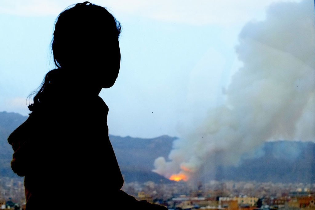 (من الأرشيف) الطفلة أمل تشاهد تعرض منزلها  للقصف الجوي في صنعاء، اليمن، في أبريل 2015.