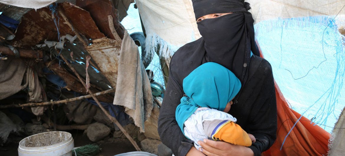 On 8 August 2016 in Yemen, an internally displaced woman sits with her daughter in front of her makeshift shelter in the Tharawan IDP camp on the outskirts of Sana’a. By 11 August 2016, over 2.8 million internally displaced persons (IDPs) had fled their homes due to ongoing conflict.