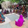 A community health worker in a pink sari leads a prenatal care education session for a group of women in a rural village.
