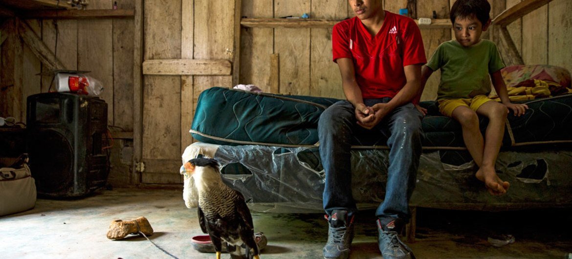 Alexis, 18, with his brother Wilson, 6, and their pet, a Caracara, at home in Omoa, Honduras.