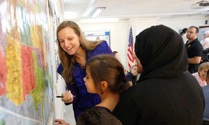 Young Syrian refugees study a map of the United States at the International Organization for Migration (IOM) Amman, Jordan, office.