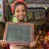बांग्लादेश में, एक यूनीसेफ़ समर्थित स्कूल में, एक विकलांग बच्ची अपनी शिक्षा प्रगति दर्शाते हुए.