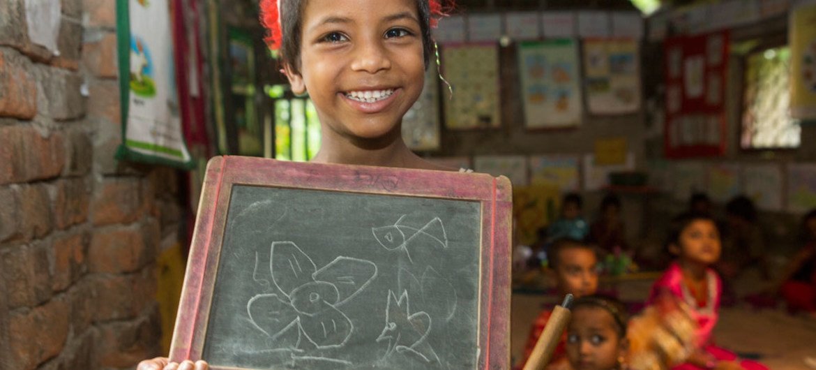 Une enfant confrontée à un handicap tient une ardoise pour montrer ses capacités de dessin dans une école soutenue par l'UNICEF dans le village de Soyghoria, au Bangladesh.