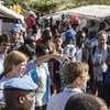 A group of UN officials and peacekeepers in blue berets visit a Protection of Civilians (POC) site in a refugee camp.