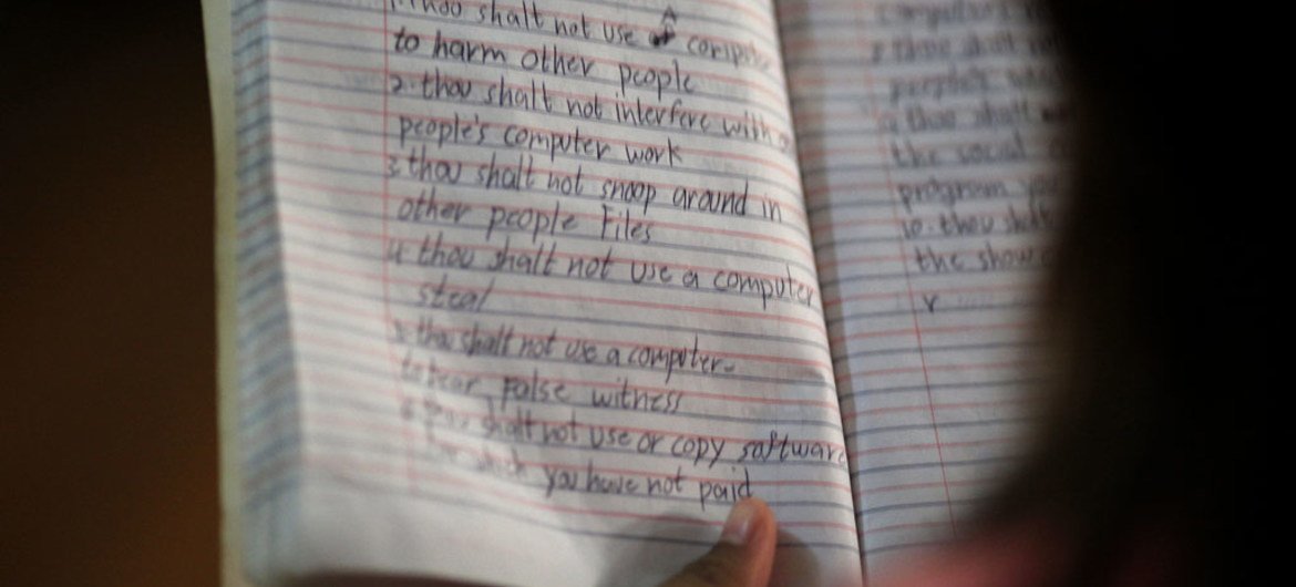 कंप्यूटर साक्षरता और नैतिकता वर्ग के दौरान एक लड़की अपनी नोटबुक से पढ़ती है