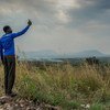Беженец из Южного Судана в Уганде пытается поймать сигнал для своего мобильного телефона.