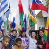 Cheerful young students in their traditional dress proudly waive their national flags during the Peace Bell ceremony of the observance of the International Day of Peace at UN Headquarters in New York.