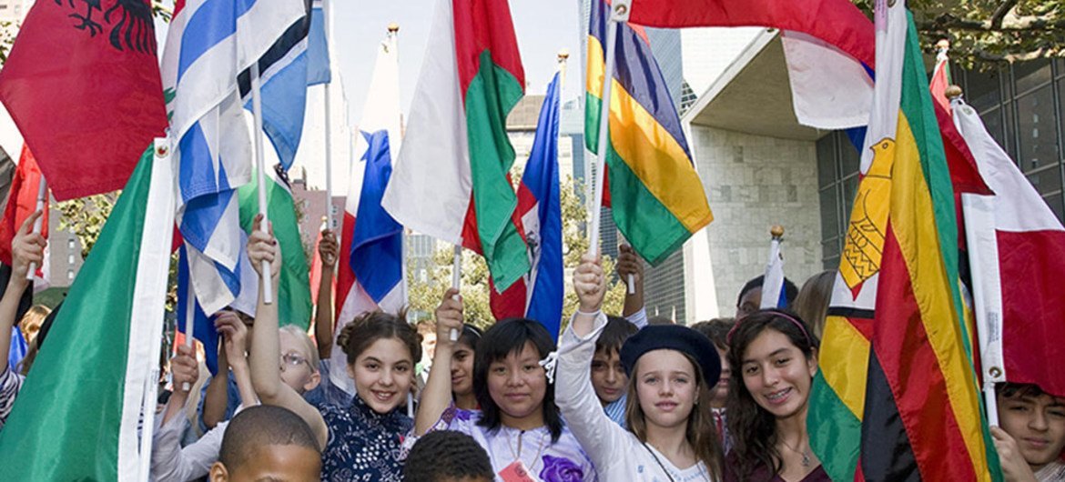Estudiantes, con las vestimentas tradicionales de sus países, muestran sus banderas en la celebración del Día Internacional de la Paz, en la sede de la ONU en Nueva York. Foto: ONU//Paulo Filgueiras