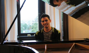 Ayham al-Ahmad sits behind his piano.
