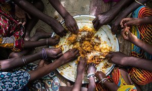 Children's hands hurry to the lunch cooked by Artou and Fatime: rice and fish. Village of Tagal, Lake Chad region, Chad. UNICEF/ Tremeau