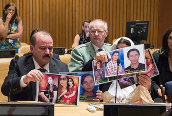 Participants at a UNODC event in New York hold up photos of their missing loved ones.