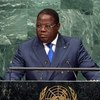 Alphonse Odinga, du Gabon, prend la parole depuis une tribune ornée de l'emblème de ONU , devant un mur de marbre vert.
