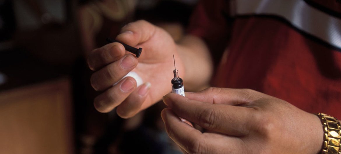 In Laos, a doctor recaps a needle in preparation for disposal, after giving a post-exposure Rabies vaccination to a boy who was scratched by a dog.