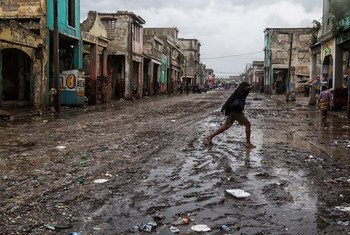 A woman crosses a muddy street in downtown Port-au-Prince after Hurricane Matthew hit Haiti on 4 October 2016, bringing  heavy rains and winds.