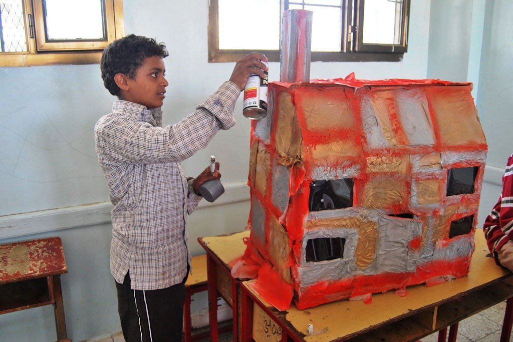也门萨达一名流离失所的男孩在为他被毁的房屋制作复制品，作为他心里健康治疗的一部分。