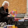 In Georgia, an elderly woman peddles her wares on a sidewalk.