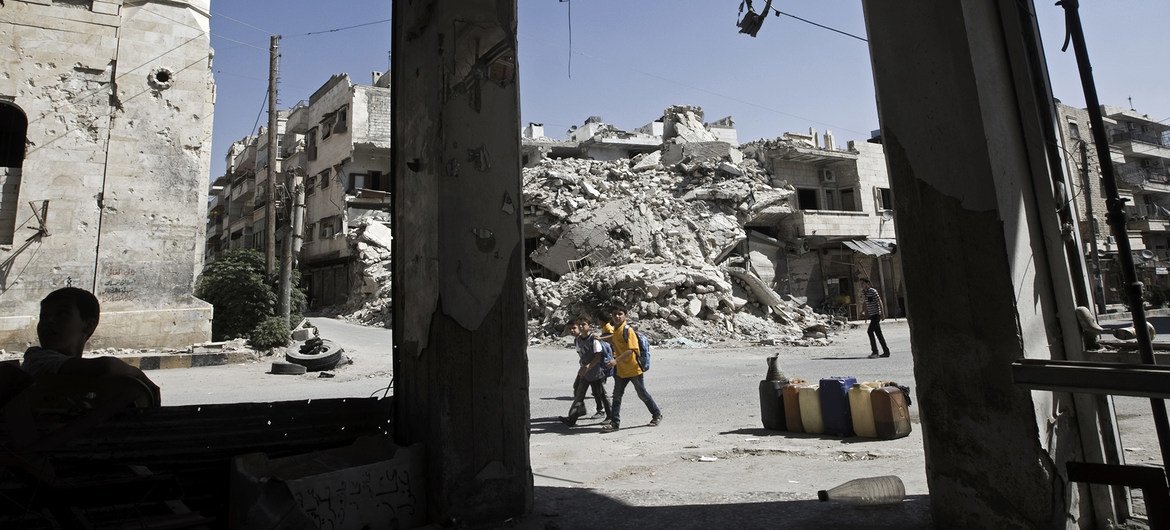 Boys pass rubble and destroyed buildings on their way to a nearby private school offering basic lessons, in the city of Maarat al-Numaan, Idlib Governorate.