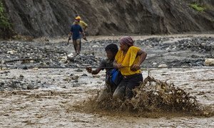 People cross a flooded river in western Haiti after a bridge was washed away by Hurricane Matthew. (file)