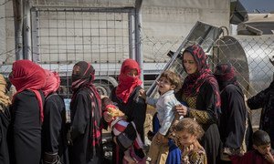 Displaced Iraqi women line up to receive food and water at Debaga camp for internally displaced people in Iraq’s Erbil Governorate.