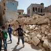 Children walk by houses destroyed by on-going fighting after their first day of school in eastern Aleppo, Syria.