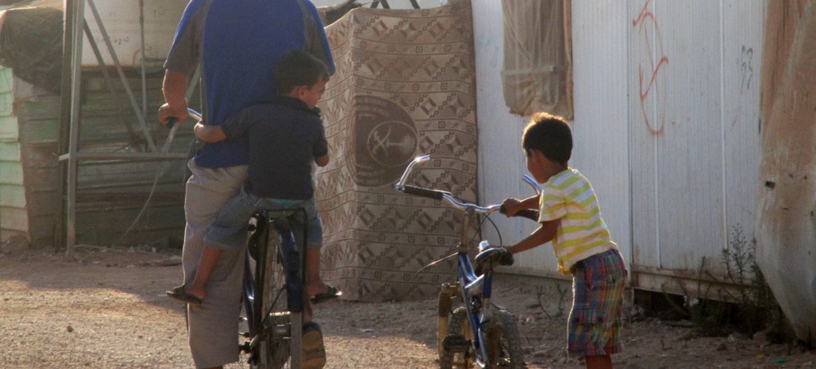 A father and his children in Jordan’s Zaatari camp prepare to travel on their bicycles.