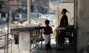 A child and a man sell baked goods in Aleppo, Syria.