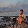 فتاة صغيرة تجلس على حطام مصنع للغراء حيث تعمل على جمع النفايات لصنع الغراء.