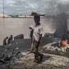 Un niño pasa frene a un punto donde queman basura y materiales de caucho en Yenagoa, Nigeria. Foto: UNICEF/Tanya Bindra
